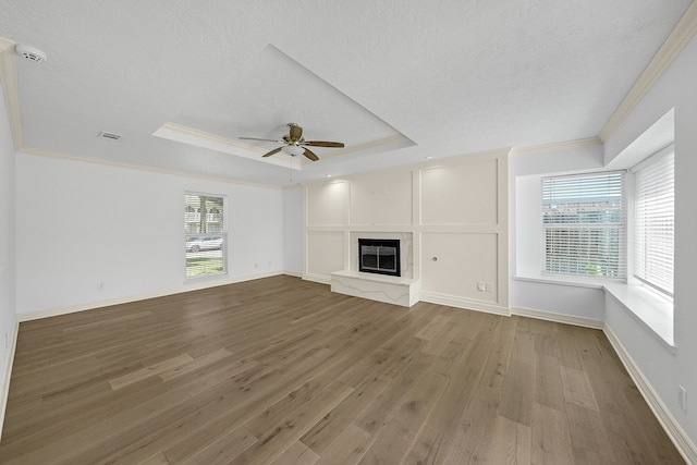 unfurnished living room featuring hardwood / wood-style floors, ceiling fan, a raised ceiling, and ornamental molding