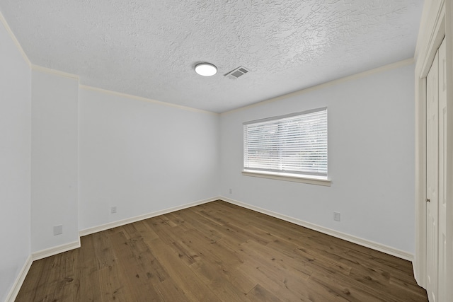 unfurnished bedroom with a textured ceiling, crown molding, and dark wood-type flooring