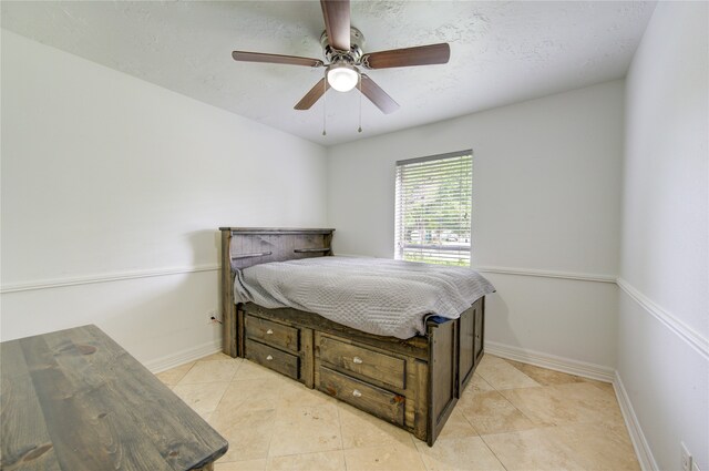 bedroom with a textured ceiling, light tile patterned floors, and ceiling fan