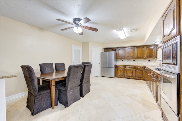 kitchen with ceiling fan, light tile patterned flooring, sink, appliances with stainless steel finishes, and decorative backsplash