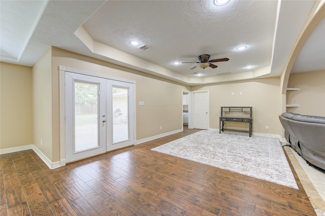 interior space featuring ceiling fan, a raised ceiling, dark wood-type flooring, and a textured ceiling