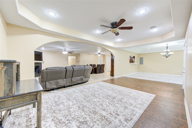 living room featuring a textured ceiling, ceiling fan with notable chandelier, a fireplace, and hardwood / wood-style floors