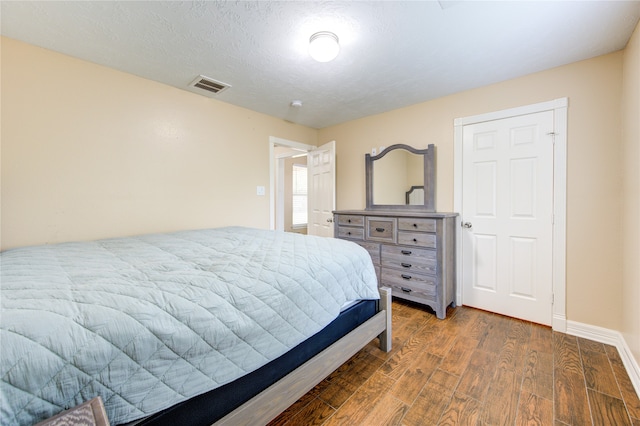 bedroom featuring a textured ceiling and dark hardwood / wood-style floors