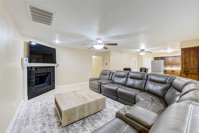 living room featuring a tiled fireplace and ceiling fan