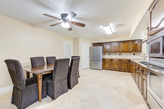 kitchen featuring ceiling fan, light tile patterned floors, sink, backsplash, and stainless steel appliances