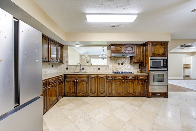 kitchen with stainless steel appliances, a textured ceiling, tasteful backsplash, and sink