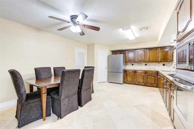 kitchen with ceiling fan, light tile patterned floors, sink, appliances with stainless steel finishes, and decorative backsplash