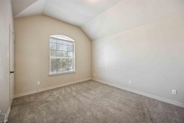 carpeted empty room featuring vaulted ceiling