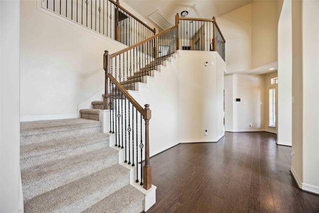 stairs with wood-type flooring and a towering ceiling