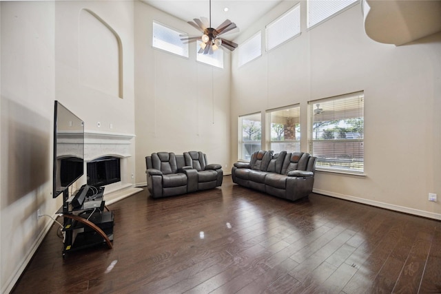 living room with ceiling fan, wood-type flooring, and a high ceiling