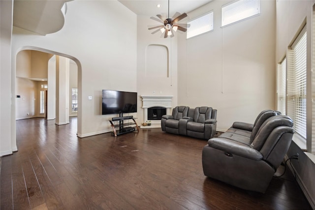 living room with ceiling fan, a high ceiling, and dark hardwood / wood-style floors