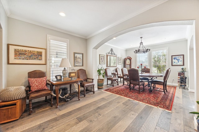 dining space featuring wood-type flooring, ornamental molding, and a notable chandelier