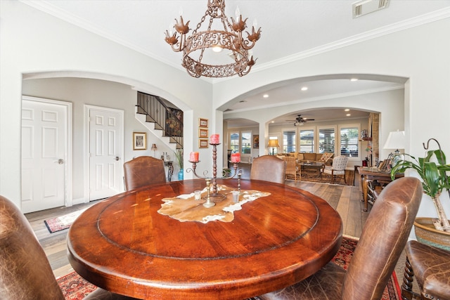 dining room with ceiling fan with notable chandelier, ornamental molding, and hardwood / wood-style floors