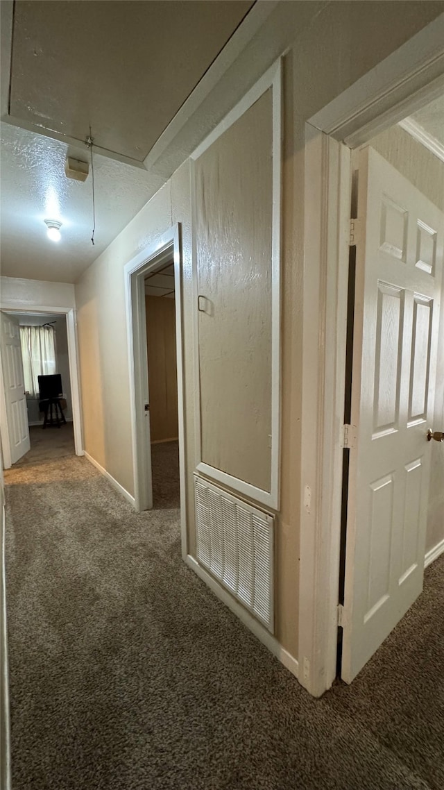 hallway featuring a textured ceiling and carpet