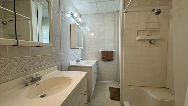 bathroom with vanity, a drop ceiling, tile patterned floors, walk in shower, and tile walls