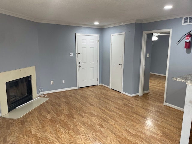 unfurnished living room featuring a textured ceiling, ornamental molding, and light hardwood / wood-style flooring