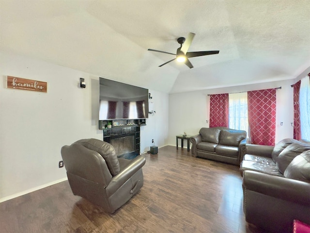 living room with a fireplace, a textured ceiling, lofted ceiling, ceiling fan, and dark hardwood / wood-style floors