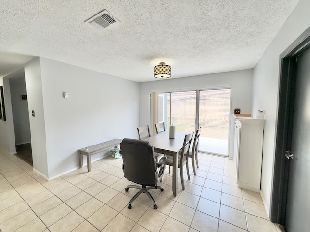 tiled dining room featuring a textured ceiling