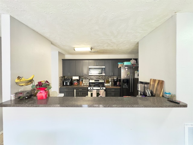 kitchen with gray cabinetry, backsplash, a textured ceiling, and appliances with stainless steel finishes