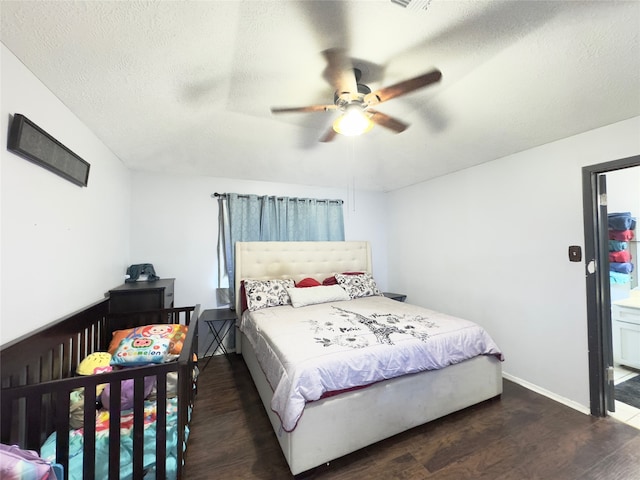 bedroom with a textured ceiling, ceiling fan, and dark wood-type flooring