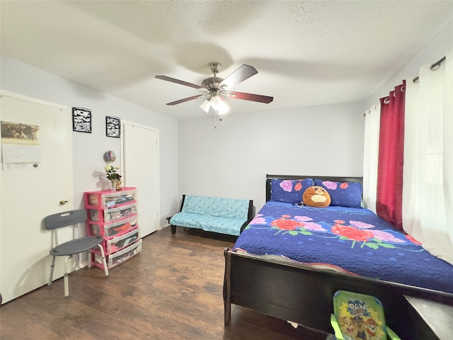 bedroom with a textured ceiling, ceiling fan, and dark hardwood / wood-style flooring