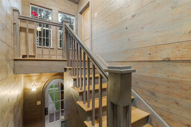 stairway featuring wood walls