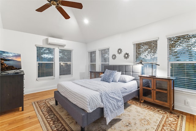 bedroom featuring a wall mounted air conditioner, light wood-type flooring, vaulted ceiling, and ceiling fan