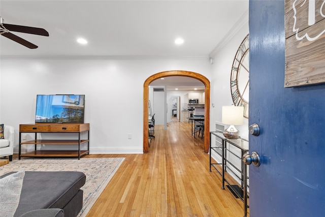 interior space with ceiling fan, wood-type flooring, and ornamental molding