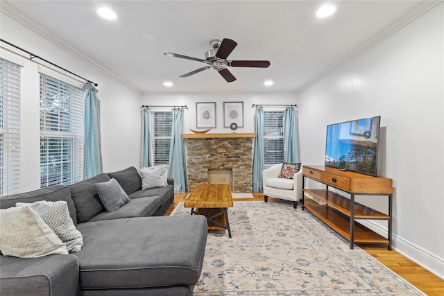 living room featuring hardwood / wood-style flooring, ceiling fan, ornamental molding, and a fireplace