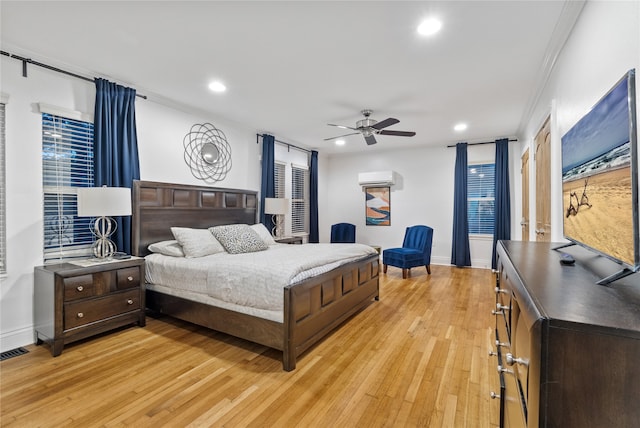 bedroom with ceiling fan, light hardwood / wood-style floors, ornamental molding, and a wall unit AC