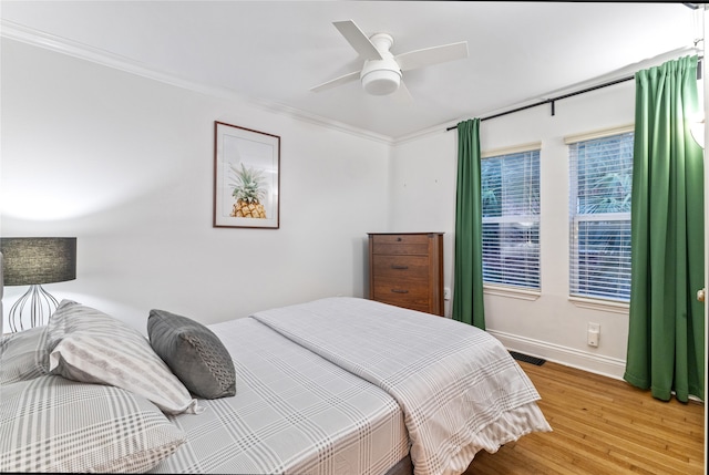 bedroom with hardwood / wood-style floors, ceiling fan, and crown molding