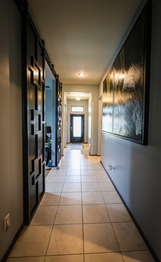 hall with light tile patterned floors and a barn door