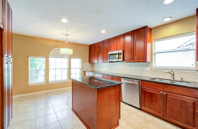 kitchen with a healthy amount of sunlight, a kitchen island, sink, and stainless steel appliances