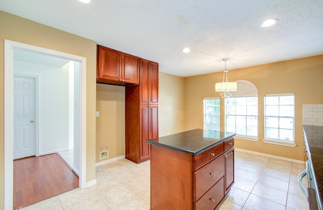 kitchen featuring a chandelier, a textured ceiling, hanging light fixtures, a kitchen island, and light tile patterned floors