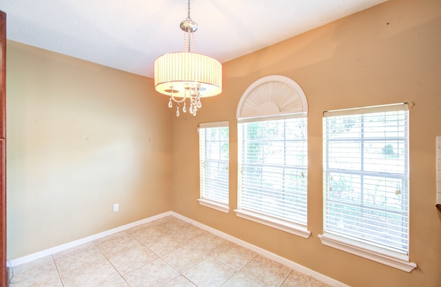 unfurnished room with light tile patterned floors and a chandelier