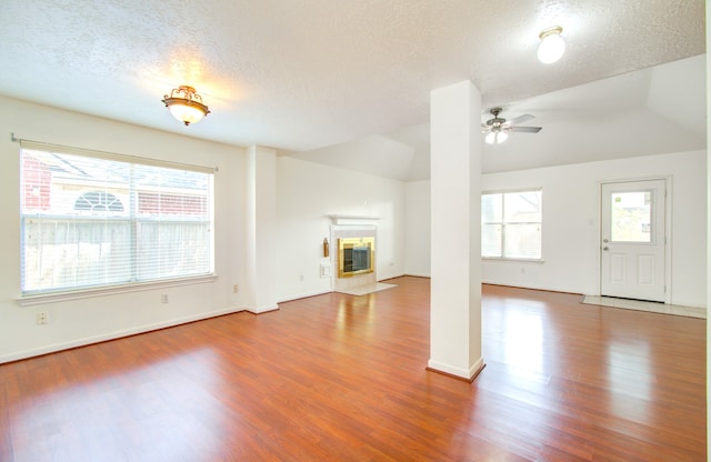 unfurnished living room with a textured ceiling, lofted ceiling, hardwood / wood-style floors, and ceiling fan