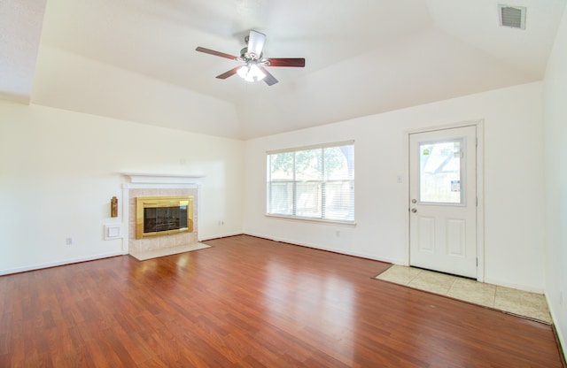 unfurnished living room with a tile fireplace, lofted ceiling, hardwood / wood-style floors, and ceiling fan