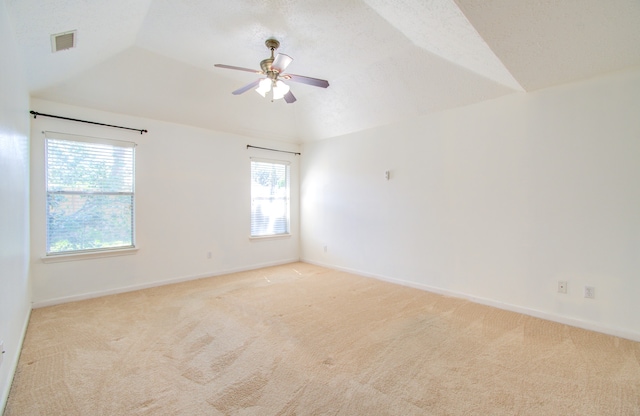 empty room with ceiling fan, lofted ceiling, light carpet, and a wealth of natural light