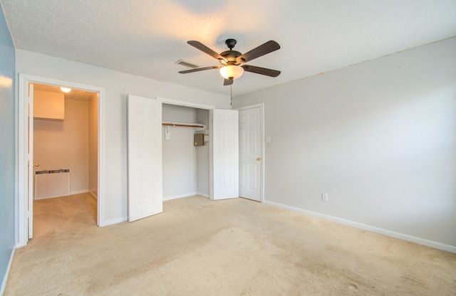 unfurnished bedroom featuring a closet, ceiling fan, light colored carpet, and a textured ceiling