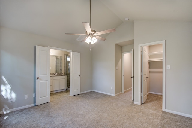 unfurnished bedroom with a closet, vaulted ceiling, light carpet, a walk in closet, and ceiling fan