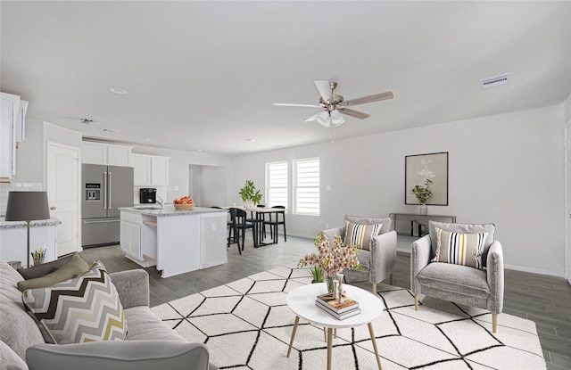 living room featuring wood-type flooring, ceiling fan, and sink