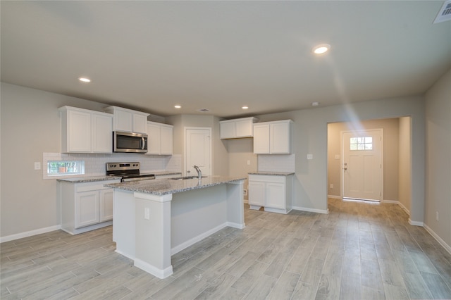 kitchen featuring white cabinets, stainless steel appliances, light wood-type flooring, and light stone countertops