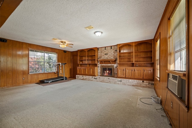 unfurnished living room featuring light carpet, a brick fireplace, ceiling fan, and wooden walls