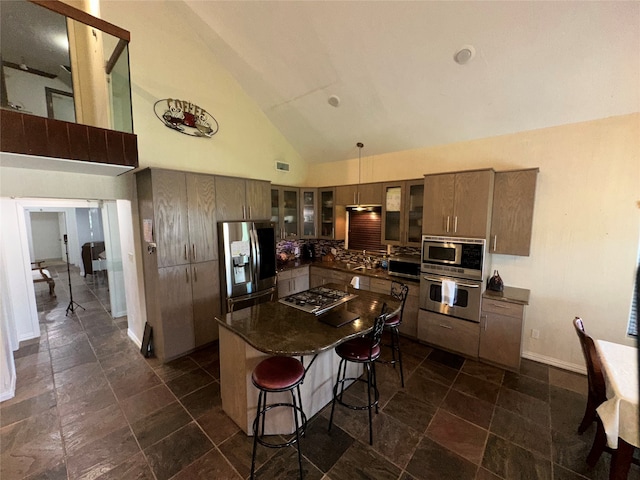 kitchen featuring hanging light fixtures, high vaulted ceiling, appliances with stainless steel finishes, a center island, and a breakfast bar area