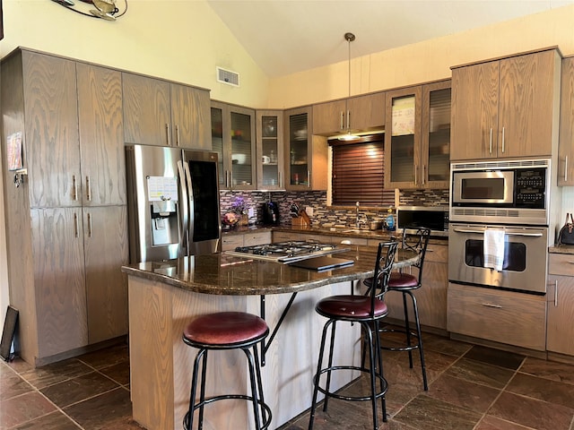 kitchen featuring dark stone counters, a breakfast bar area, a kitchen island, decorative backsplash, and stainless steel appliances