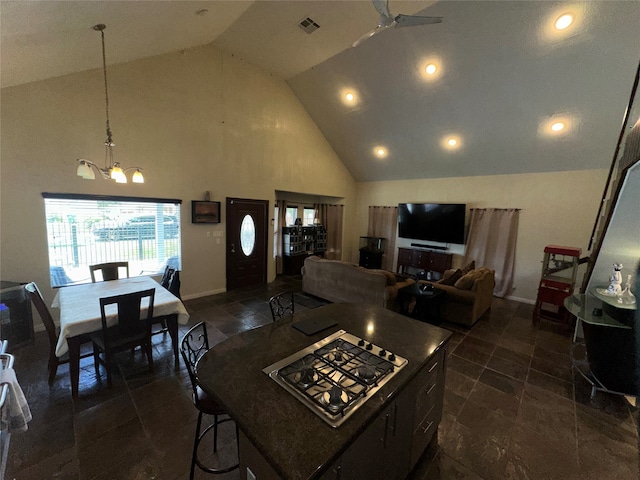 kitchen featuring hanging light fixtures, ceiling fan with notable chandelier, a center island, and high vaulted ceiling