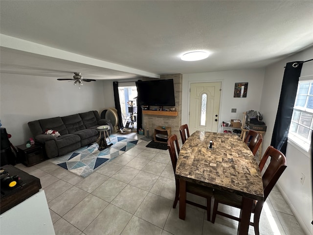 tiled dining area with ceiling fan, a stone fireplace, and a textured ceiling