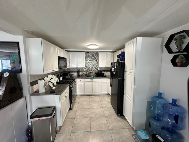 kitchen with light tile patterned floors, backsplash, white cabinetry, and black appliances