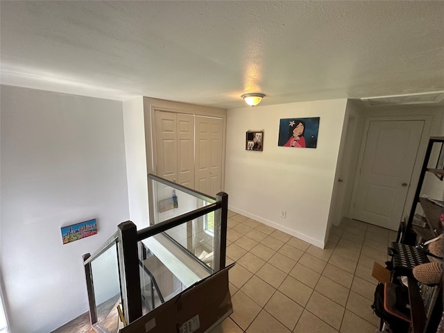 hall featuring a textured ceiling and light tile patterned floors