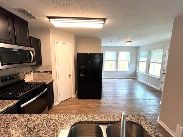 kitchen with light hardwood / wood-style floors, light stone countertops, and stainless steel appliances